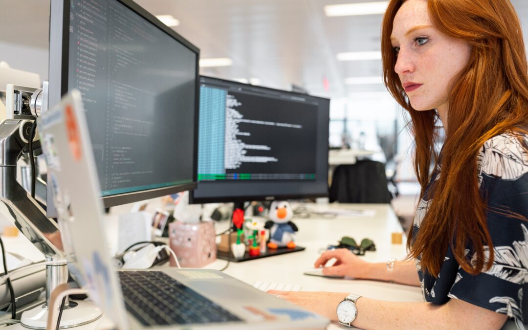a woman is looking at three monitors